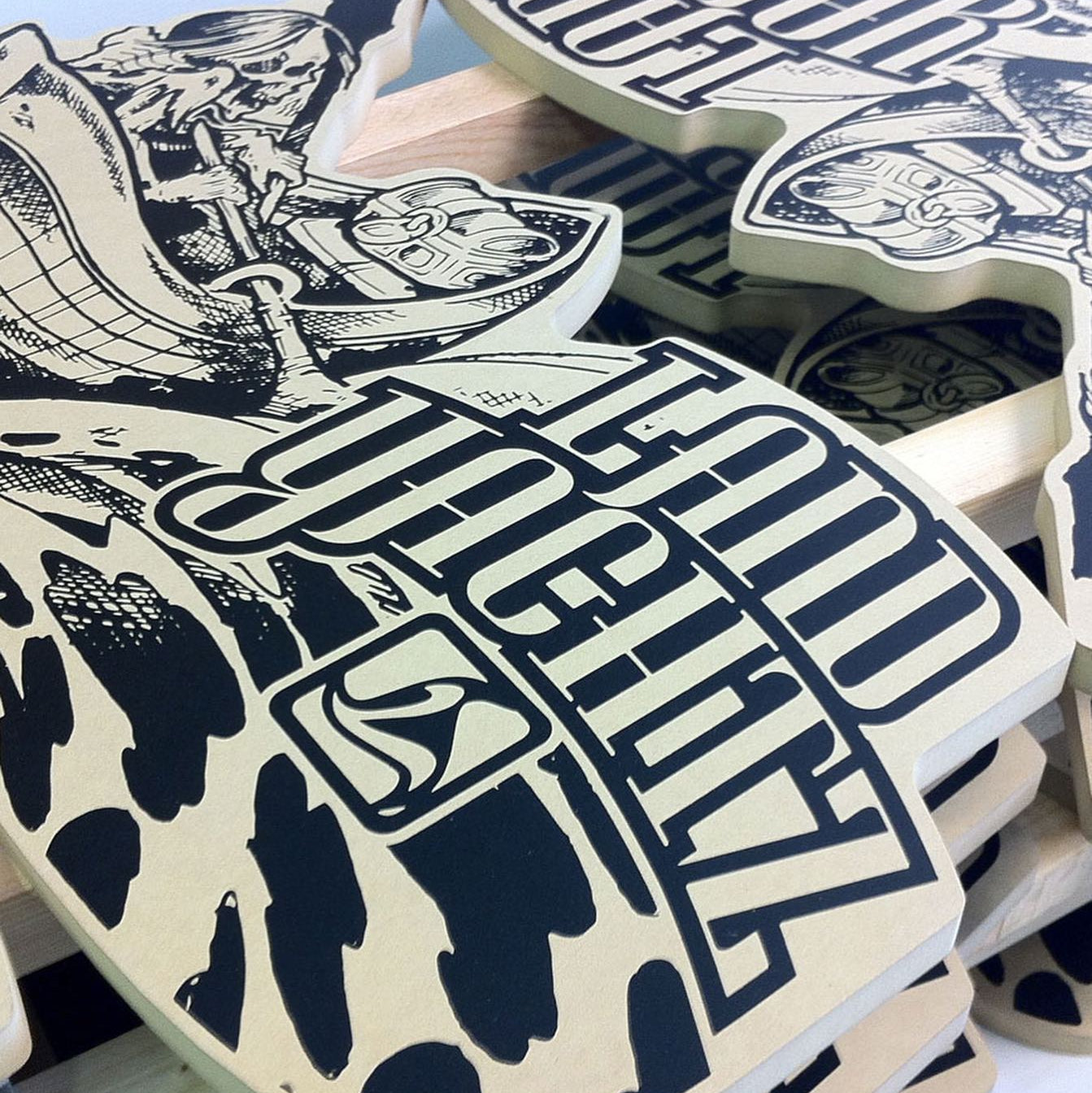 Stack of skateboard decks with graphic designs and text on a white background
